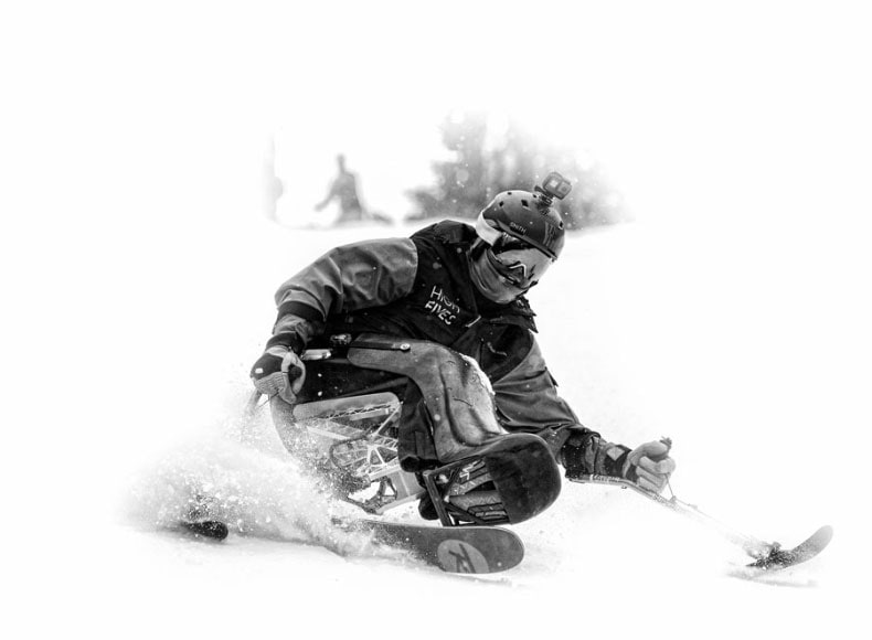 black and white adaptive skiier riding
