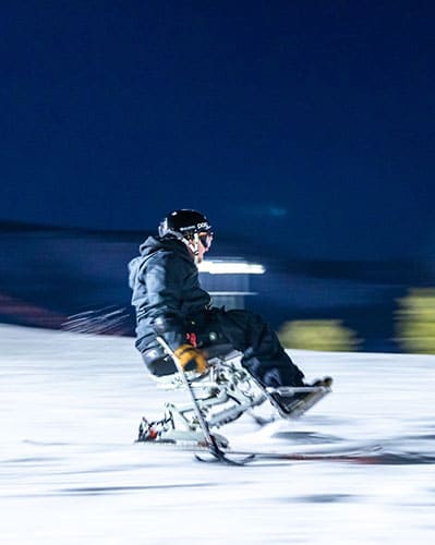 adaptive sit skiier riding at night