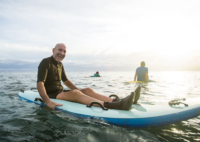 adaptive surfer sitting on board in ocean smiling and stoked
