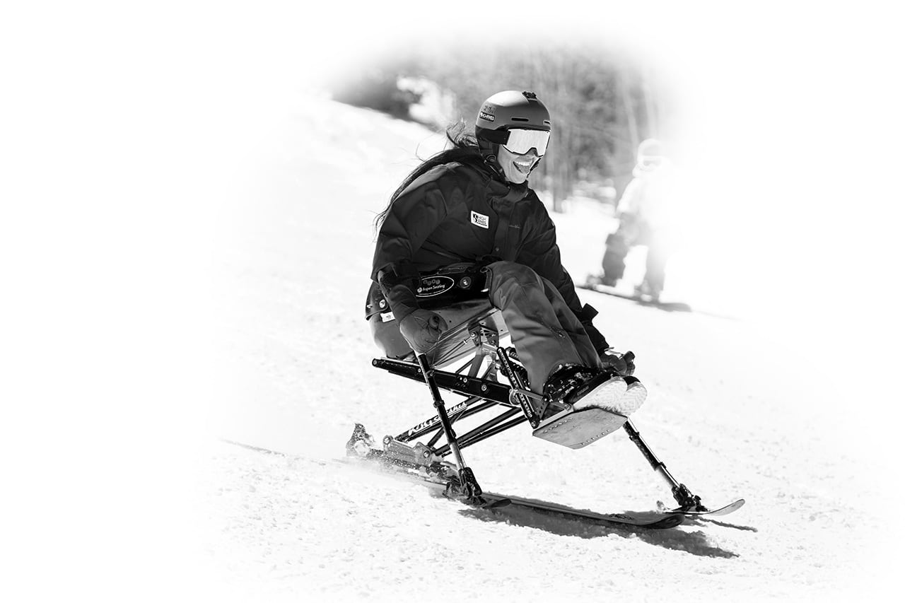 black and white adaptive skiier riding sit ski