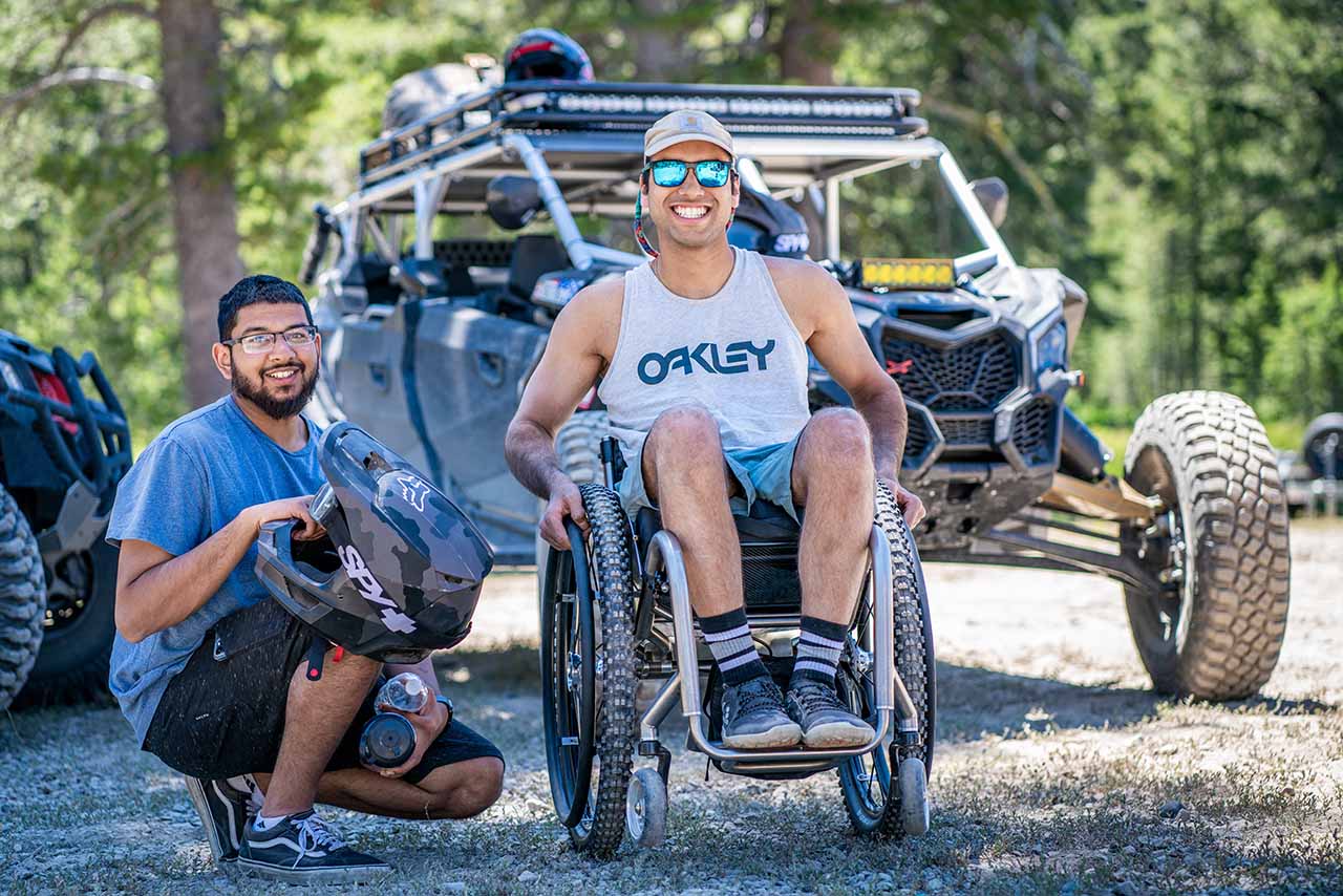 adaptive athlete and friend in front of side by side 4x4 can am
