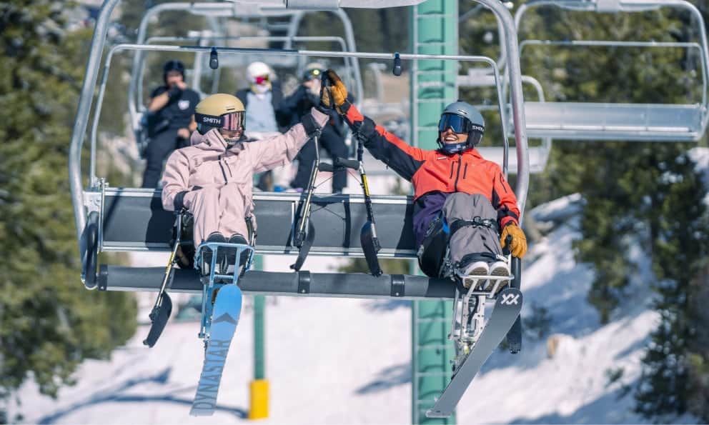 adaptive skiiers high five on chairlift
